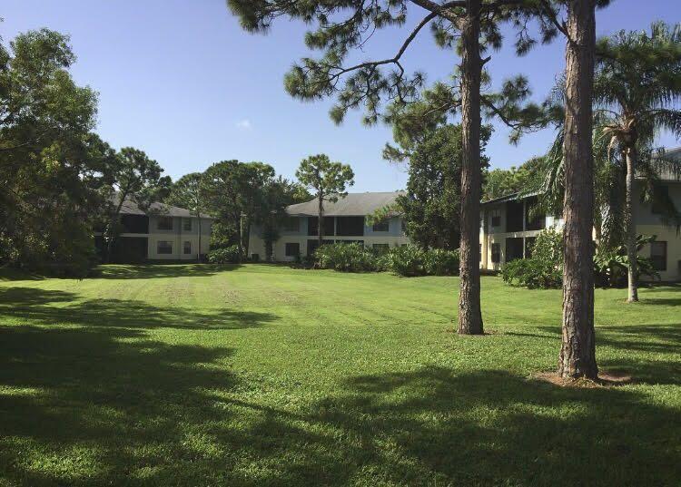 A grassy lawn sits in front of multi-story apartment buildings surrounded by trees — 6553 SE Federal Highway # 203, Stuart FL 34997, STUART, FL