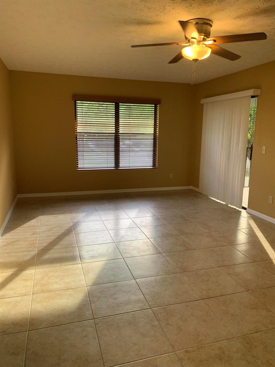 An empty room with tan walls, tile flooring, a ceiling fan, and a sliding glass door — 6553 SE Federal Highway # 203, Stuart FL 34997, STUART, FL