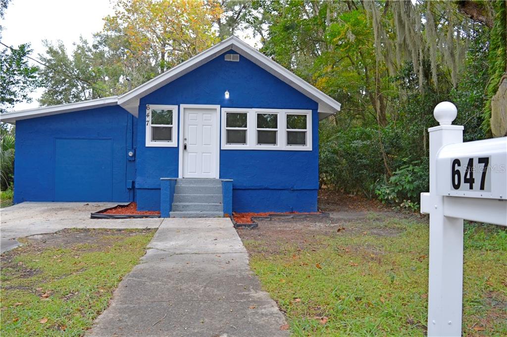 A bright blue, single-story house with a white door and a concrete walkway — 647 S DELAWARE AVENUE, DELAND, FL