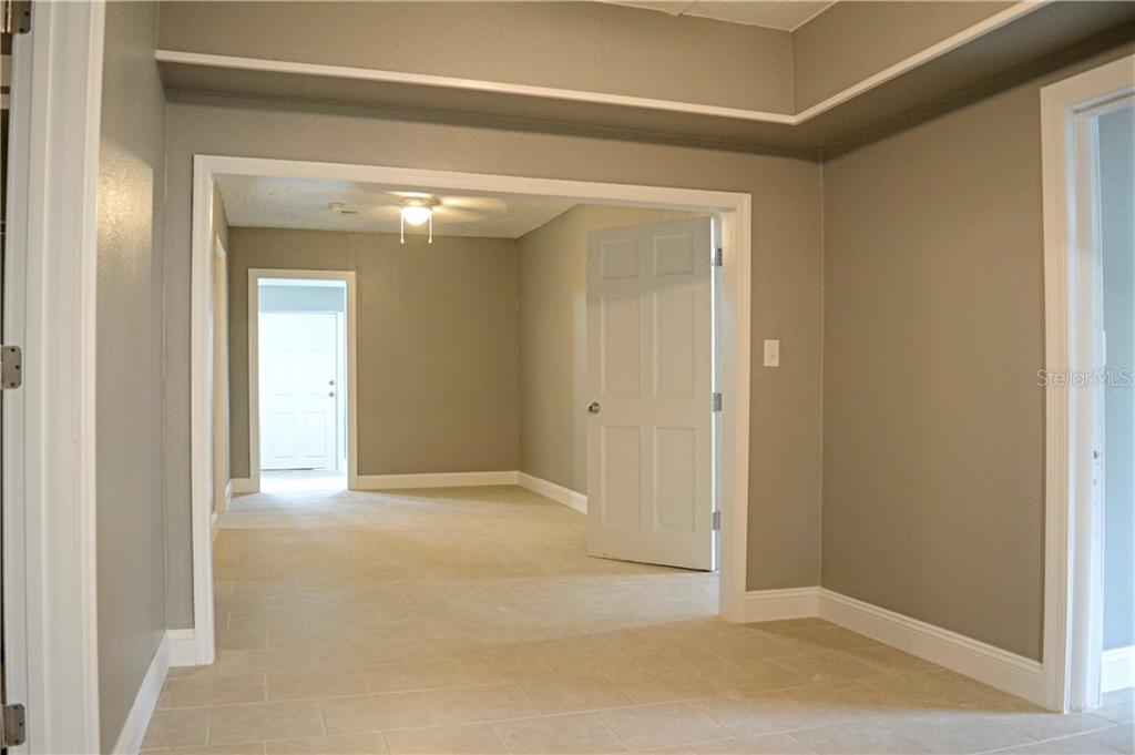 An interior view shows a tiled room leading into another space through a wide doorway — 647 S DELAWARE AVENUE, DELAND, FL
