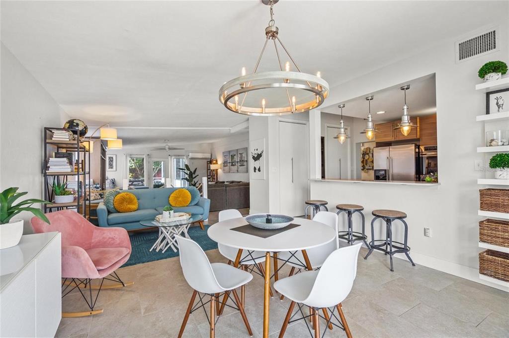 A bright open-concept living and dining area features a modern chandelier and kitchen breakfast bar — 4801 SARASOTA AVENUE, SARASOTA, FL
