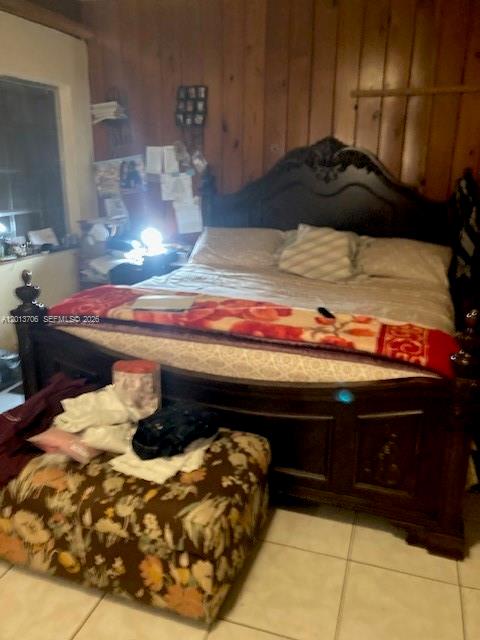 A bedroom features a dark wood bed frame, a floral ottoman, and wood-paneled walls — 321 NW 145th St, Miami FL 33168, MIAMI, FL