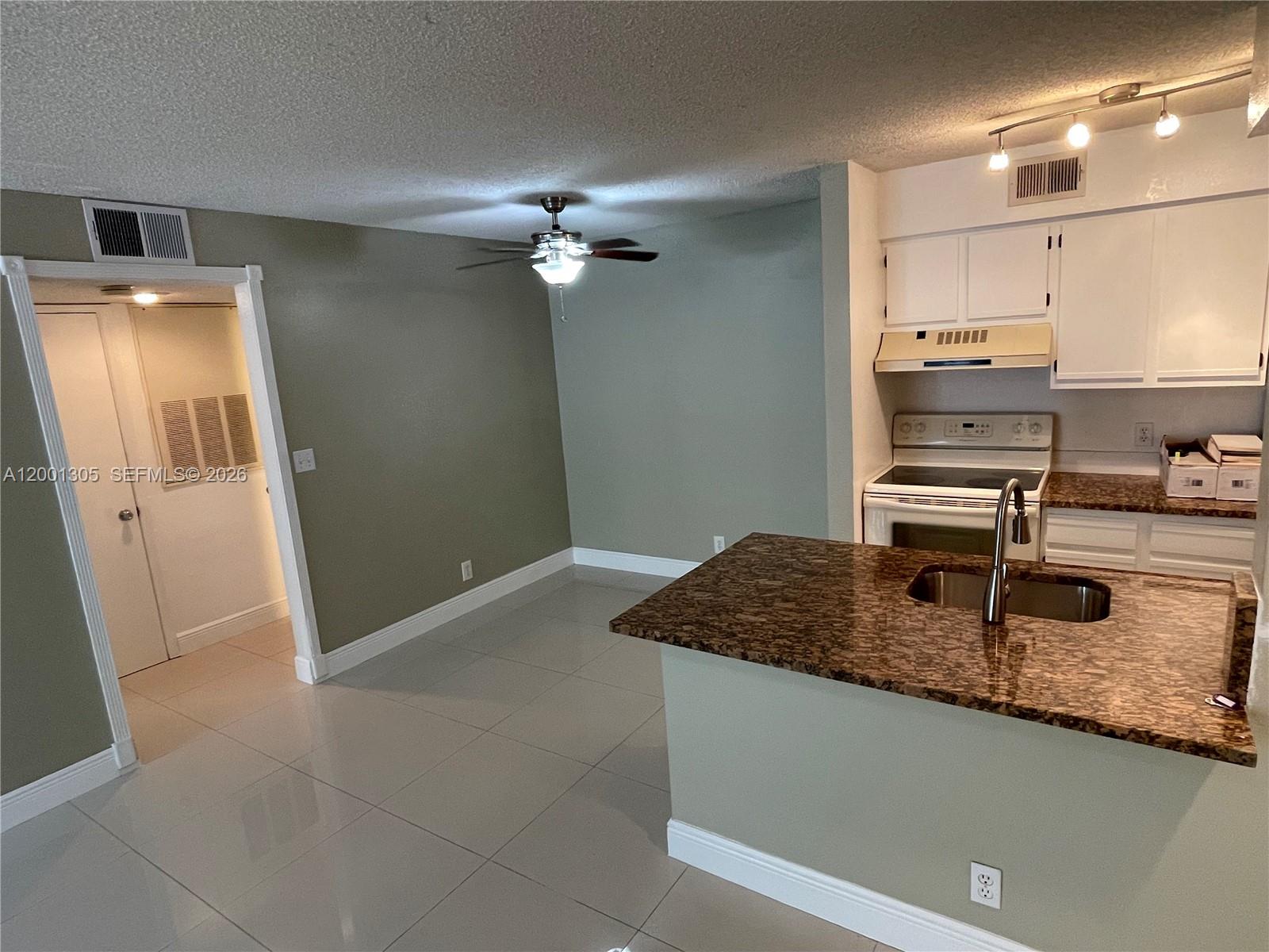A kitchen with granite countertops and white cabinets opens to a dining area with tile — 2826 S University Dr # 3101, Davie FL 33328, DAVIE, FL