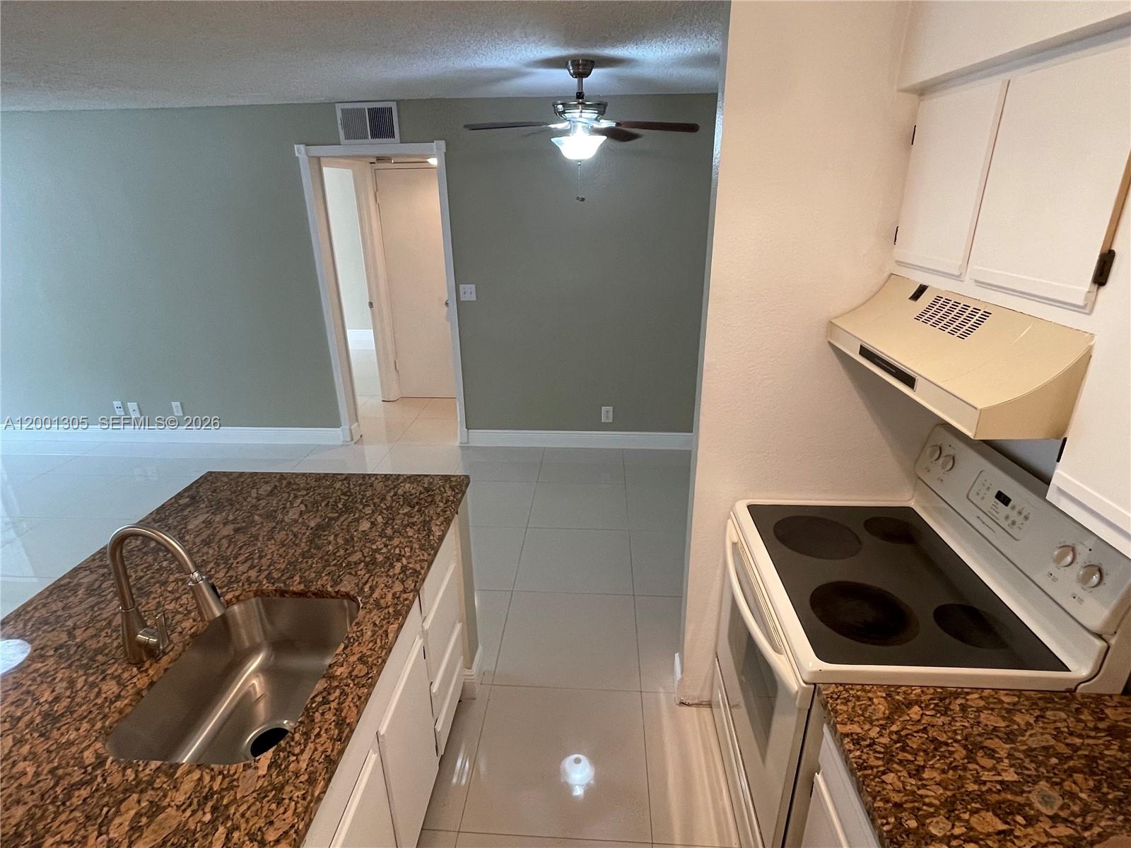 A kitchen features granite countertops, white cabinets, and a stainless steel sink — 2826 S University Dr # 3101, Davie FL 33328, DAVIE, FL