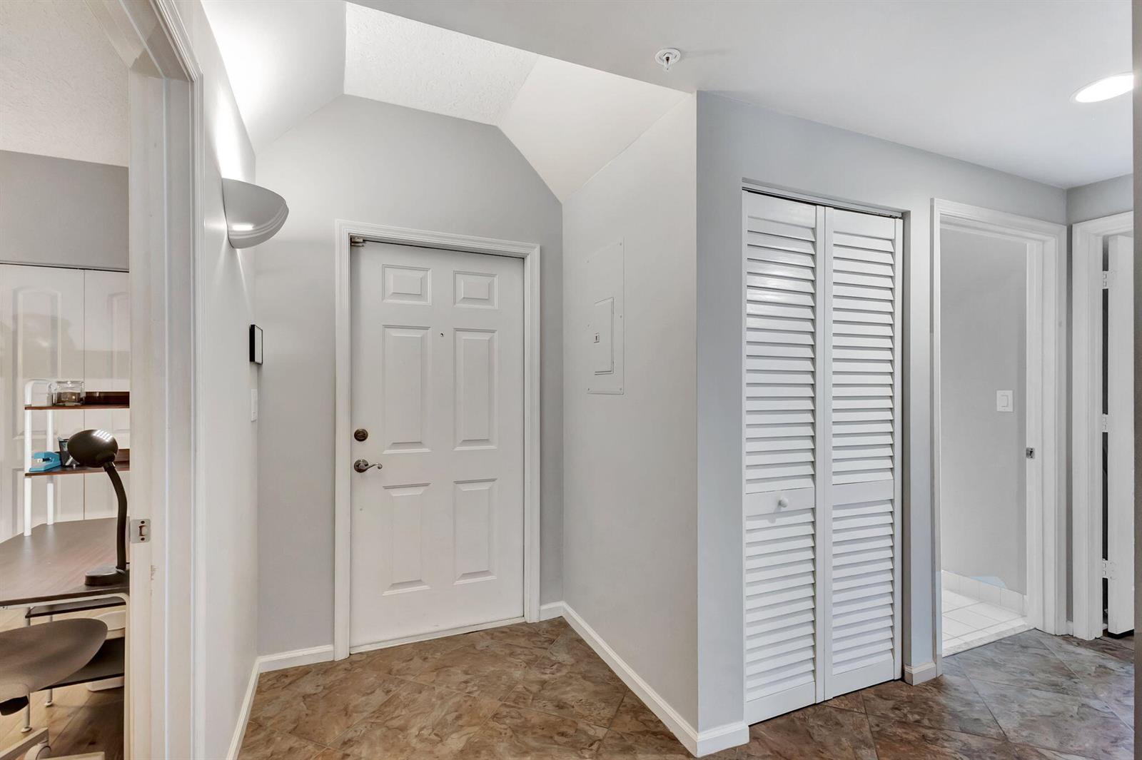 A bright entryway features a white front door, a louvered closet, and tiled flooring — 300 Uno Lago Drive # 101, Juno Beach FL 33408, JUNO BEACH, FL