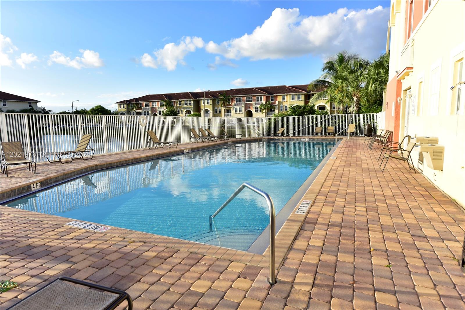 A rectangular swimming pool is surrounded by a brick paver deck and a white fence — 10850 NW 89th Ter # 5, Doral FL 33178, DORAL, FL