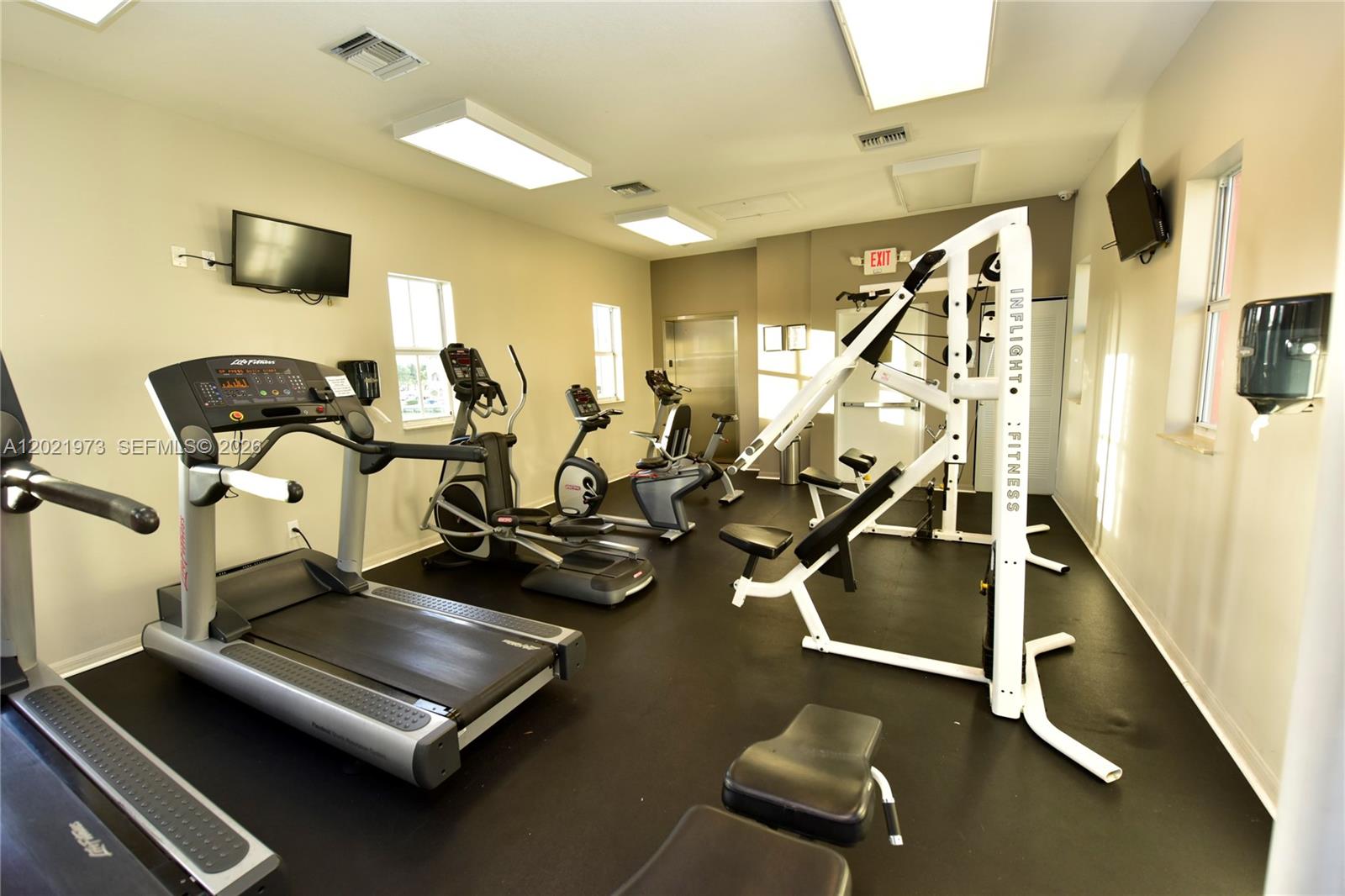 A fitness room features a treadmill, elliptical, stationary bike, and a multi-station weight machine — 10850 NW 89th Ter # 5, Doral FL 33178, DORAL, FL