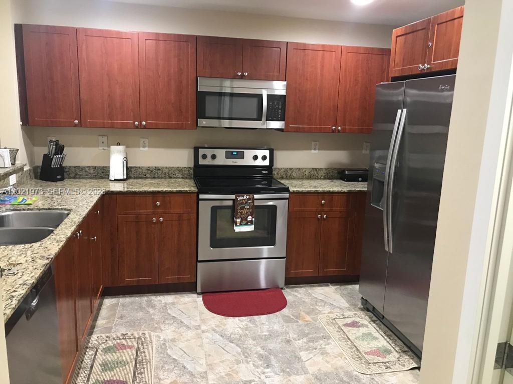 A kitchen features cherry wood cabinets, stainless steel appliances, and granite countertops — 10850 NW 89th Ter # 5, Doral FL 33178, DORAL, FL