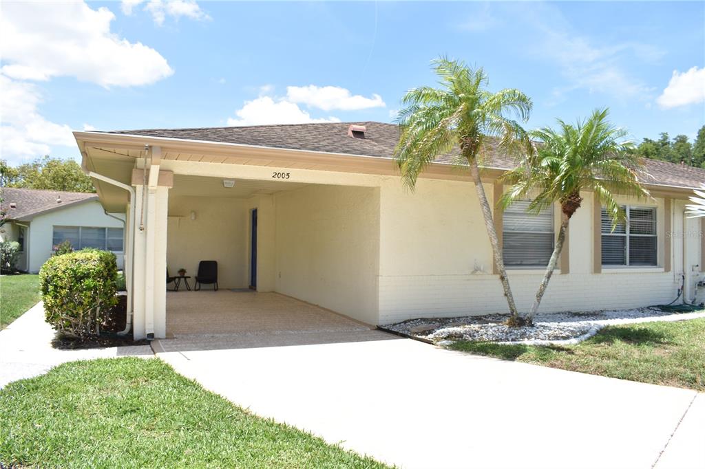 A single-story house with a carport, two palm trees, and a concrete driveway — 2005 HALMROCK PLACE UNIT 174, SUN CITY CENTER, FL