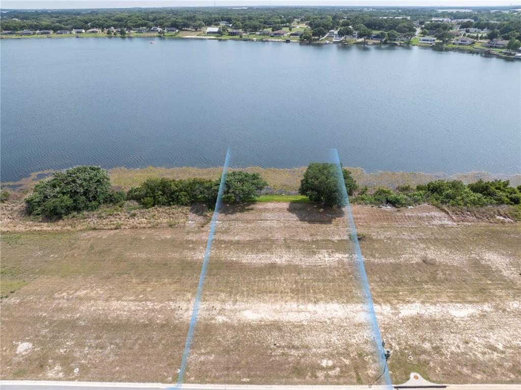 An aerial view shows a vacant, rectangular waterfront lot bordered by blue lines — 4359 JULIANA LAKE DRIVE, AUBURNDALE, FL