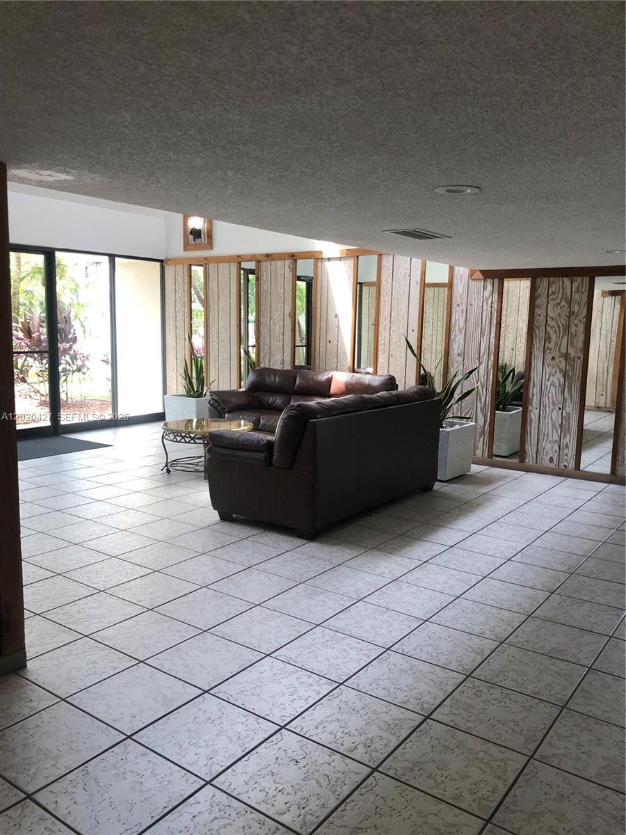 A lobby features light-colored tile flooring, wood-paneled walls with mirrors, and a dark leather sofa — 210 Lakeview Dr # 207, Weston FL 33326, WESTON, FL