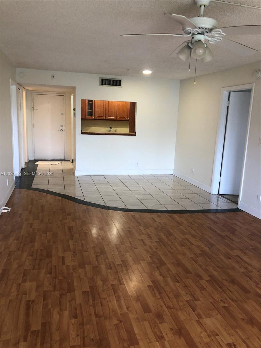 An interior view shows a living area with wood-look flooring, a tiled entryway, and a kitchen pass-through — 210 Lakeview Dr # 207, Weston FL 33326, WESTON, FL