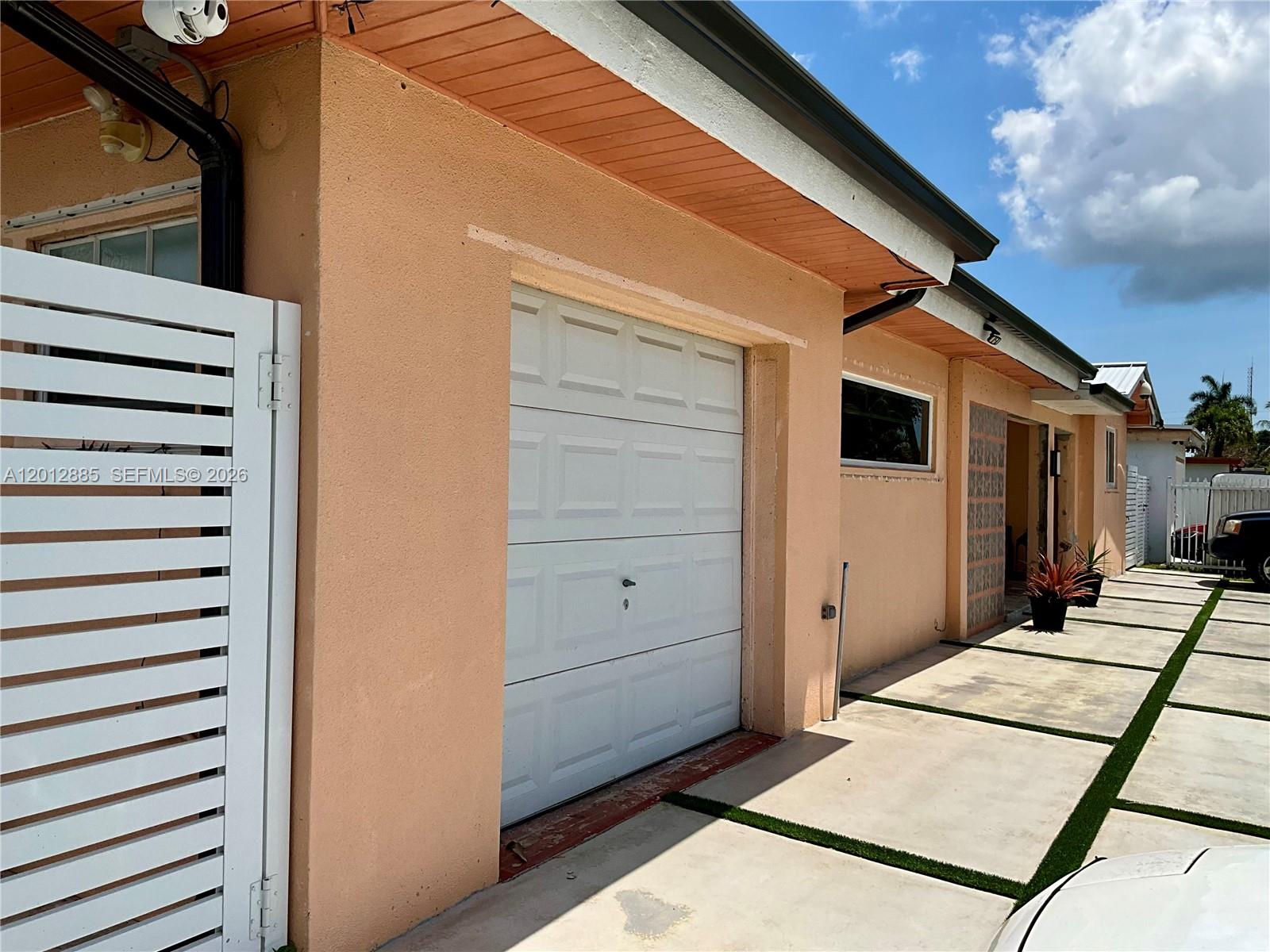 The exterior of a peach-colored house features a white garage door and a concrete driveway — 11251 SW 181st St, Miami FL 33157, MIAMI, FL