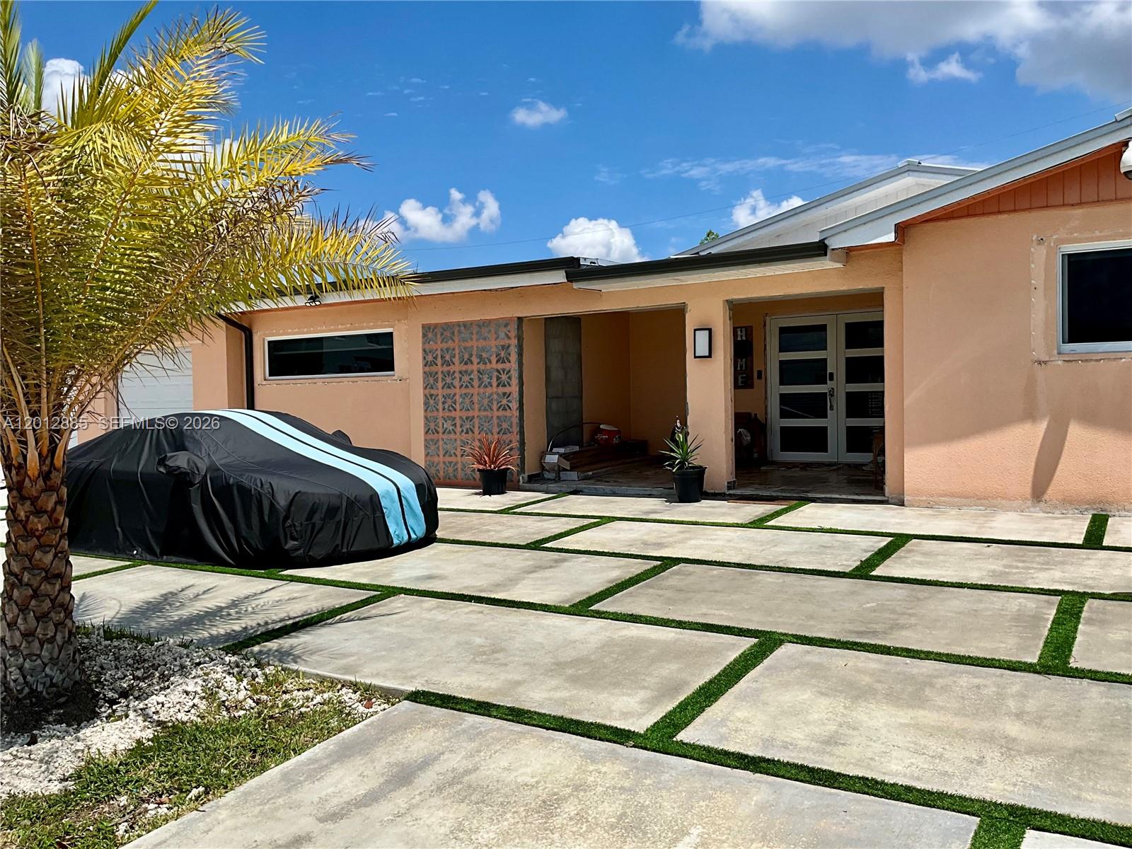 A peach-colored house features a modern concrete paver driveway with artificial grass inlays — 11251 SW 181st St, Miami FL 33157, MIAMI, FL