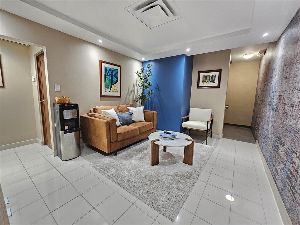 A waiting area features a brown sofa, white armchair, round coffee table, and tiled flooring — calle 8 JOSE PADILLA EL CARIBE, CIDRA, PR