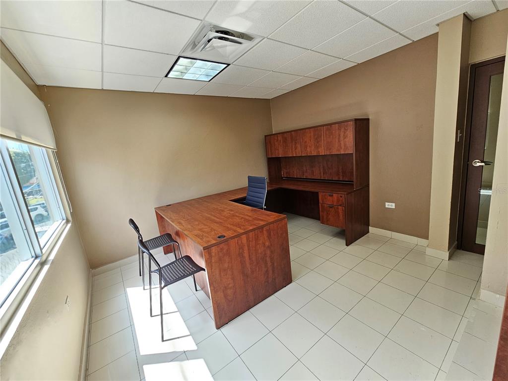 An office features a wooden L-shaped desk, a hutch, two chairs, and tiled flooring — calle 8 JOSE PADILLA EL CARIBE, CIDRA, PR