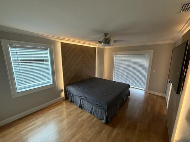 A bedroom features a wood-paneled accent wall, a ceiling fan, and light-colored hardwood flooring — 23153 SW 53rd Avenue, Boca Raton FL 33433, BOCA RATON, FL