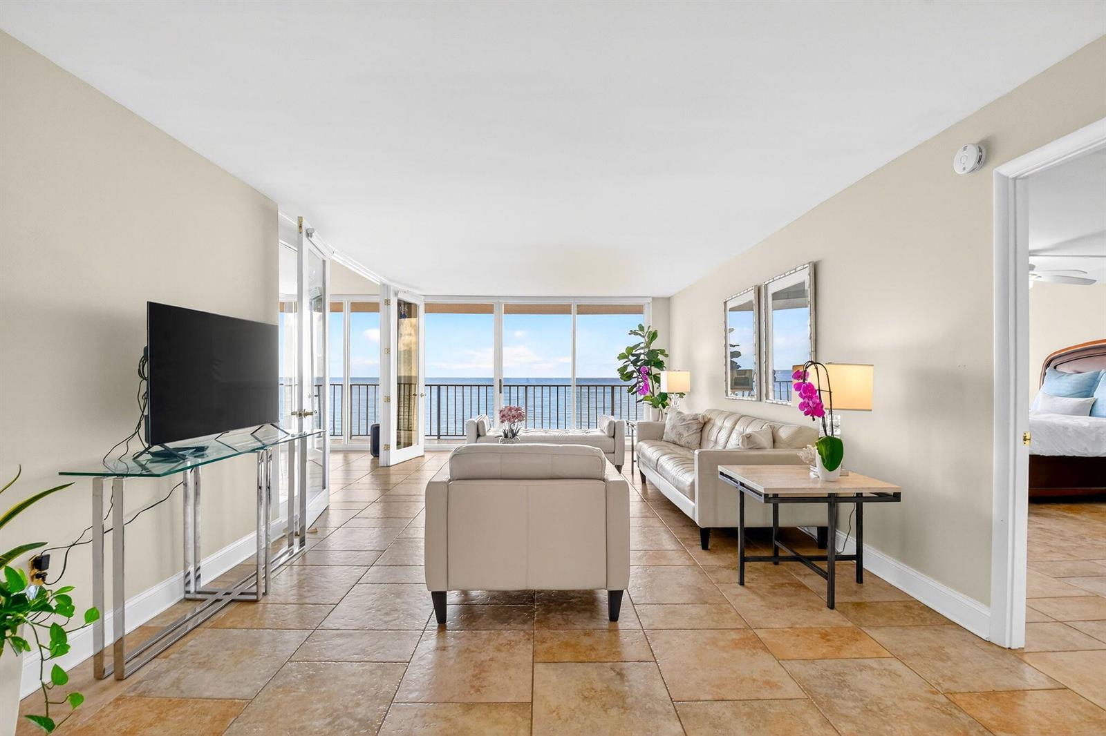 A living room with tile floors, white furniture, and a balcony overlooking the ocean — 3456 S Ocean Boulevard # 5020, Palm Beach FL 33480, PALM BEACH, FL