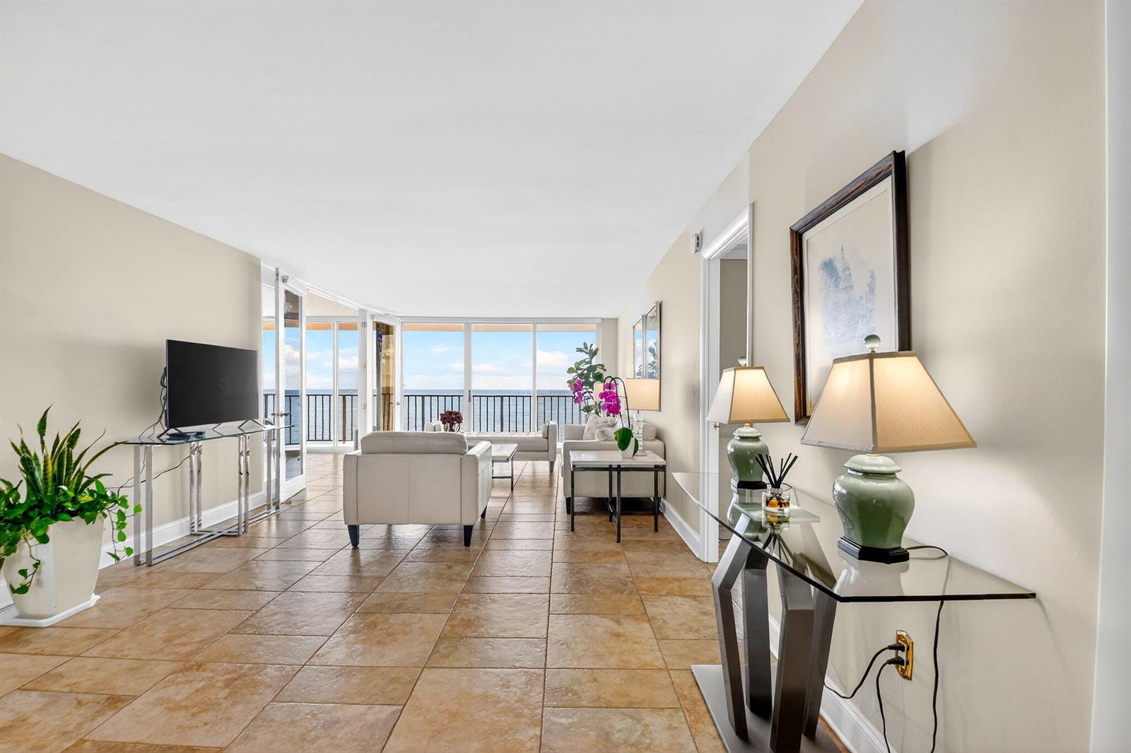 A bright living room features tile floors, a glass console table, and a balcony view — 3456 S Ocean Boulevard # 5020, Palm Beach FL 33480, PALM BEACH, FL