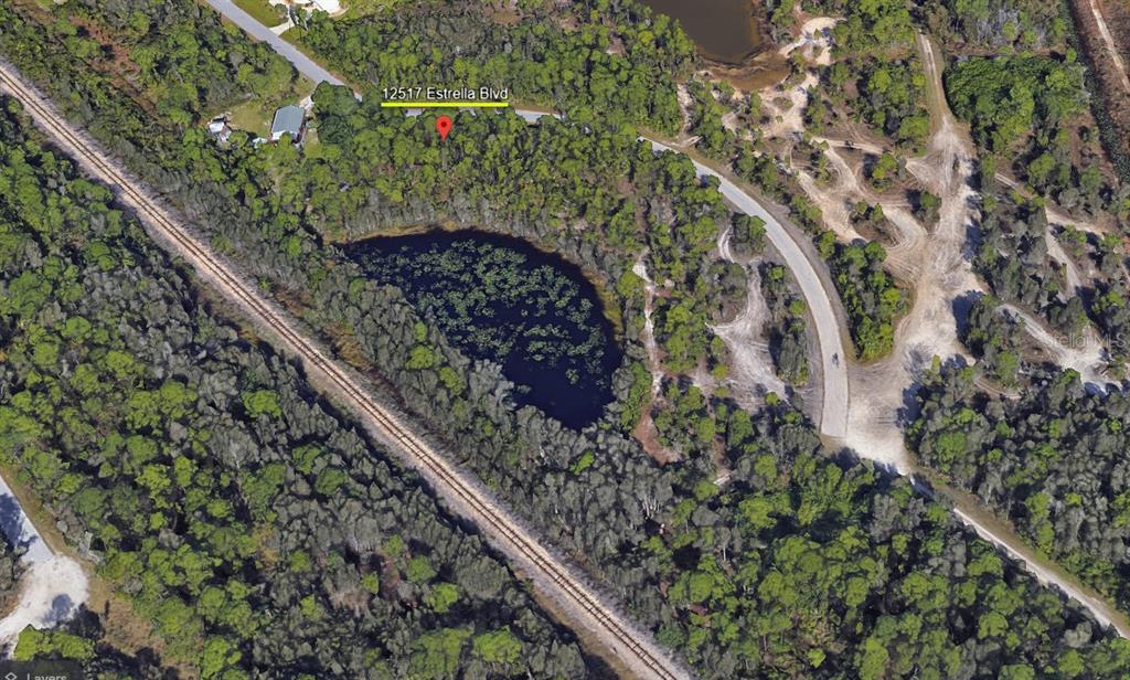 This aerial map view shows a wooded lot featuring a pond and nearby railroad tracks — 12517 ESTRELLA BOULEVARD, PUNTA GORDA, FL