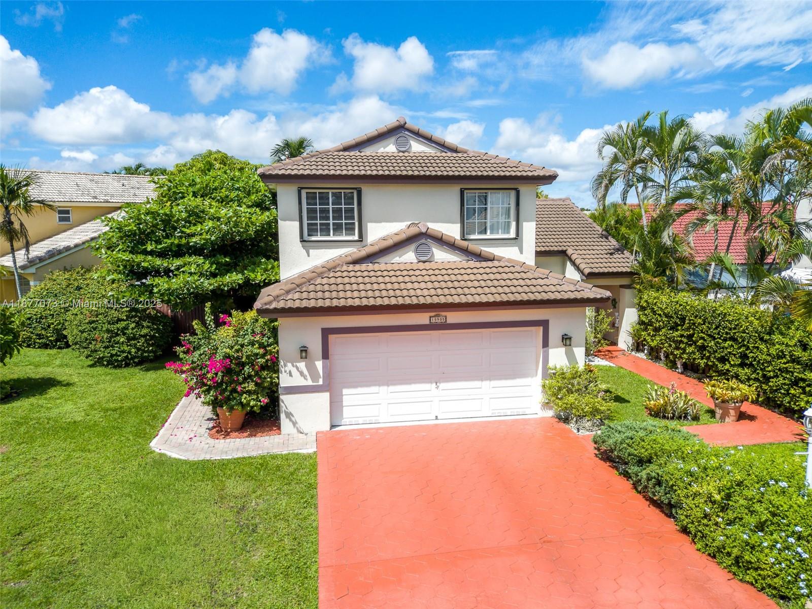 A two-story house with a tiled roof, white garage door, and a red driveway — 15905 SW 83rd Ter, Miami FL 33193, MIAMI, FL