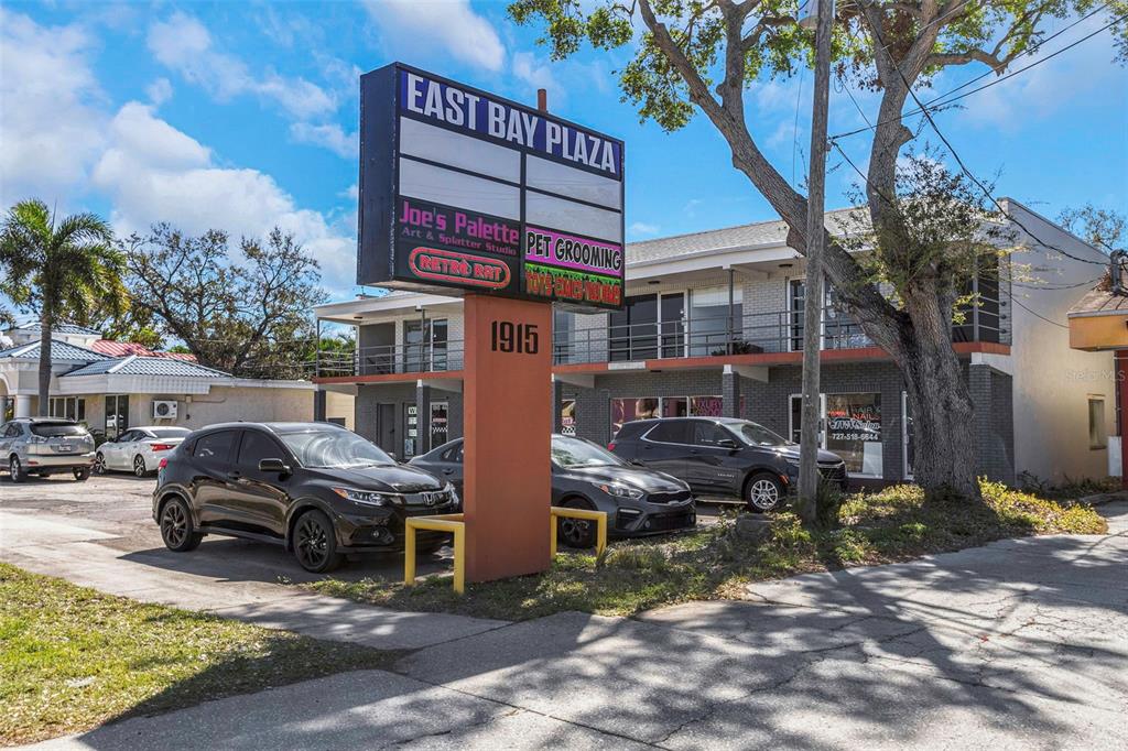 A multi-story commercial plaza building with a prominent signage pylon and a parking lot — 1915 E BAY DRIVE, LARGO, FL