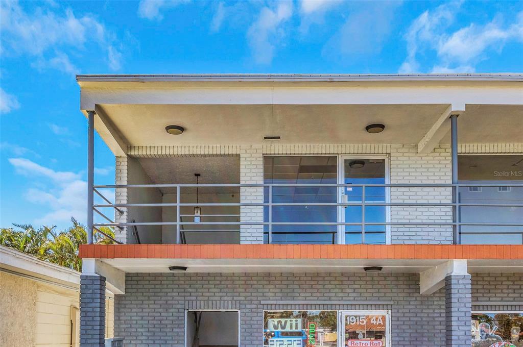 A two-story building exterior features a gray brick ground floor and a second-story balcony — 1915 E BAY DRIVE, LARGO, FL
