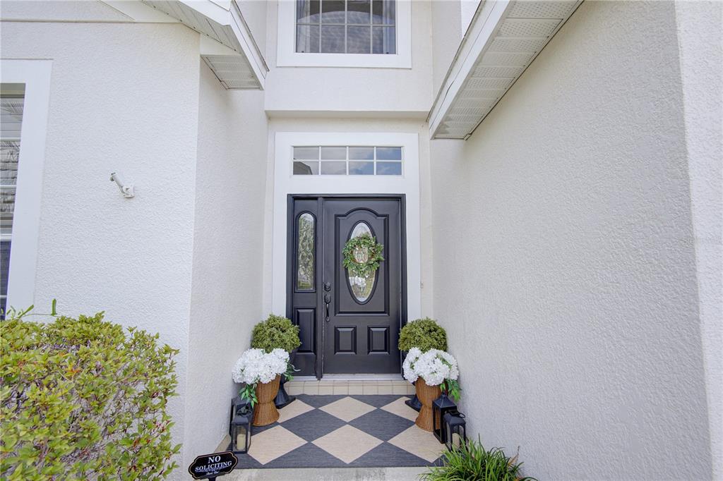 A black front door with a wreath sits under a covered entryway with checkered flooring — 963 CHERRY VALLEY WAY, ORLANDO, FL