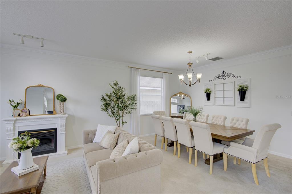 A dining and living area features a fireplace, tufted sofa, and a wooden dining table — 963 CHERRY VALLEY WAY, ORLANDO, FL