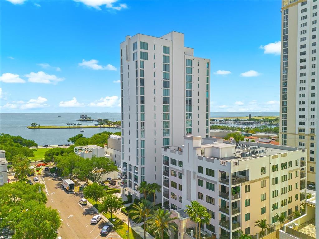 An aerial view shows a tall white residential building near a waterfront park and bay — 176 4TH AVENUE NE UNIT 201, ST PETERSBURG, FL