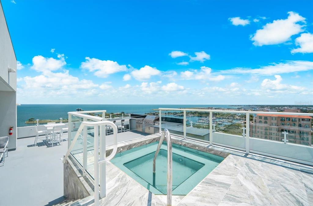 A rooftop terrace features a square hot tub, marble tiling, and a view of the ocean — 176 4TH AVENUE NE UNIT 201, ST PETERSBURG, FL