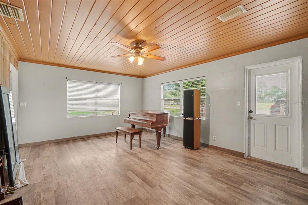 A room with wood-paneled ceilings, light-colored walls, wood-look flooring, and a grand piano — 415 LAKE JUNE ROAD, LAKE PLACID, FL