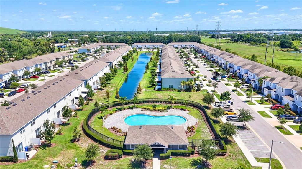 An aerial view shows a residential complex with townhomes, a central pond, and a pool — 7214 GRAND ELM DRIVE, RIVERVIEW, FL