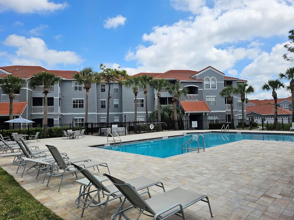 A swimming pool sits in front of a multi-story apartment building with palm trees — 18001 RICHMOND PLACE DRIVE UNIT 716, TAMPA, FL