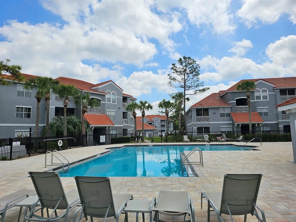 A swimming pool sits in the courtyard of a multi-story apartment complex with palm trees — 18001 RICHMOND PLACE DRIVE UNIT 716, TAMPA, FL