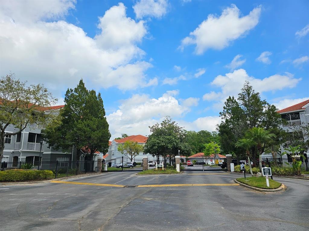 A gated entrance to a residential apartment complex with multi-story buildings under a blue sky — 18001 RICHMOND PLACE DRIVE UNIT 716, TAMPA, FL