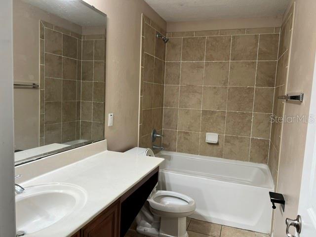 A bathroom features a white vanity, a toilet, and a bathtub with tan tiled walls — 739 REFLECTIONS LANE, WINTER GARDEN, FL