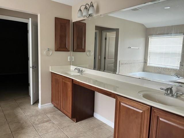 A bathroom features a double vanity with wood cabinets, a large mirror, and a tub — 739 REFLECTIONS LANE, WINTER GARDEN, FL