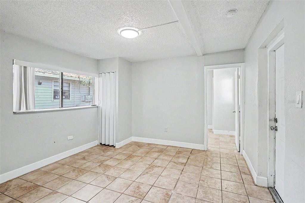 An empty room with light-colored walls, tile flooring, a window, and a doorway — 2214 QUALITY LIFE CENTER WAY, FORT MYERS, FL