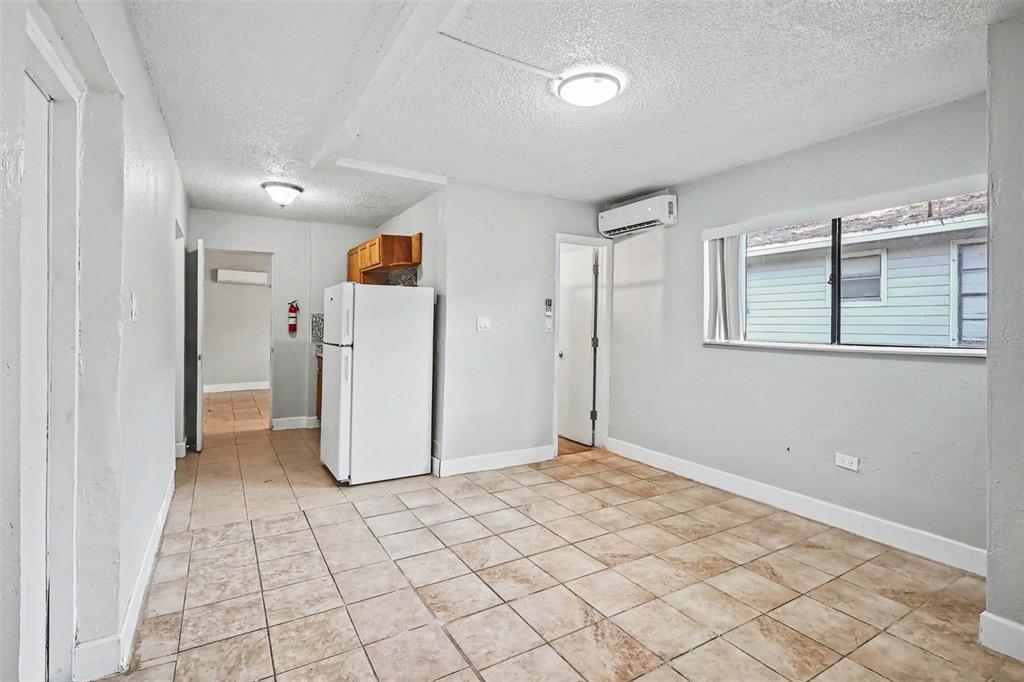 A room with light-colored tile flooring, a white refrigerator, and a wall-mounted air conditioner — 2214 QUALITY LIFE CENTER WAY, FORT MYERS, FL