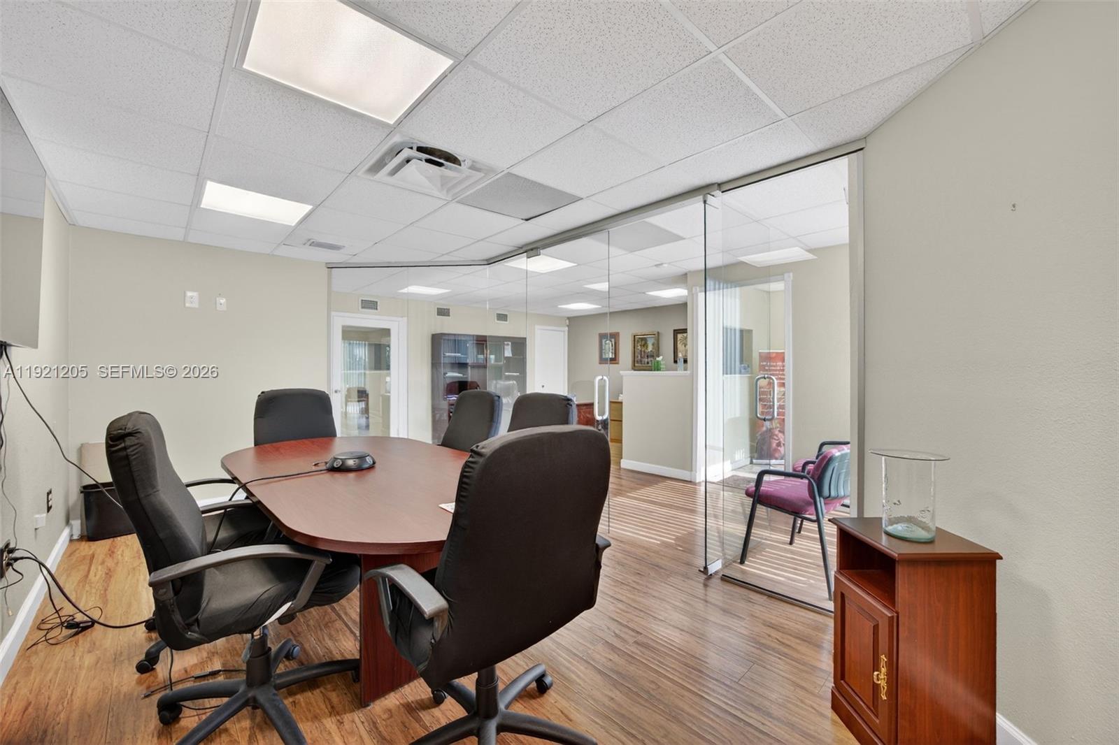 A conference room features a wooden table, black chairs, and a glass-walled office partition — 16155 SW 117th Ave # 15, Miami FL 33177, MIAMI, FL