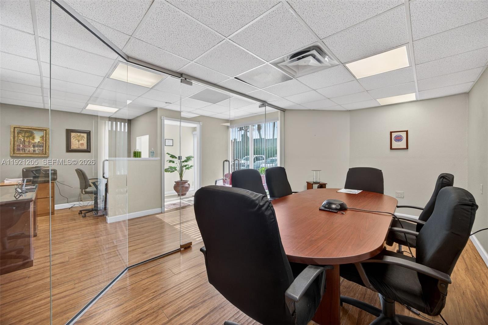 A conference room features a wood-topped table, black chairs, and a glass-walled office partition — 16155 SW 117th Ave # 15, Miami FL 33177, MIAMI, FL
