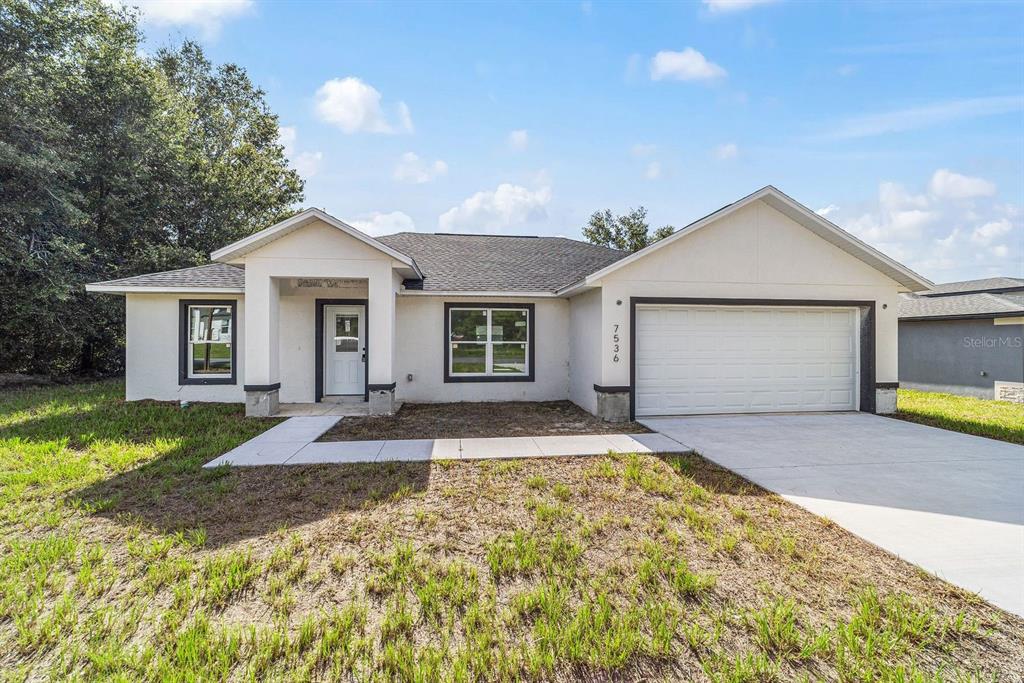 A single-story house with a white stucco exterior, a two-car garage, and a front porch — 7536 SW 129TH PLACE, OCALA, FL
