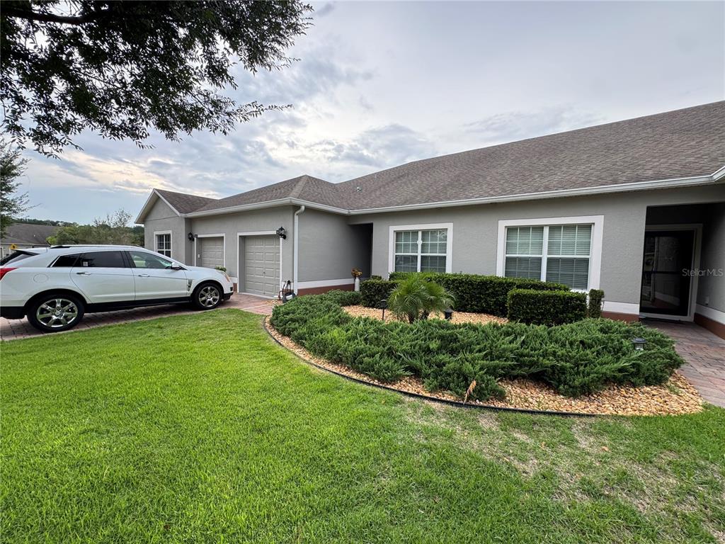 A gray house with a two-car garage, a white SUV, and a landscaped front garden — 3641 SOLANA CIRCLE UNIT B, CLERMONT, FL