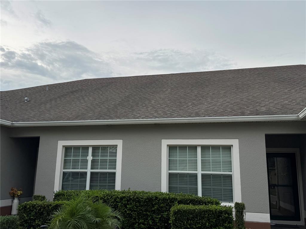 The exterior of a gray house features two windows, a front door, and a shingled roof — 3641 SOLANA CIRCLE UNIT B, CLERMONT, FL