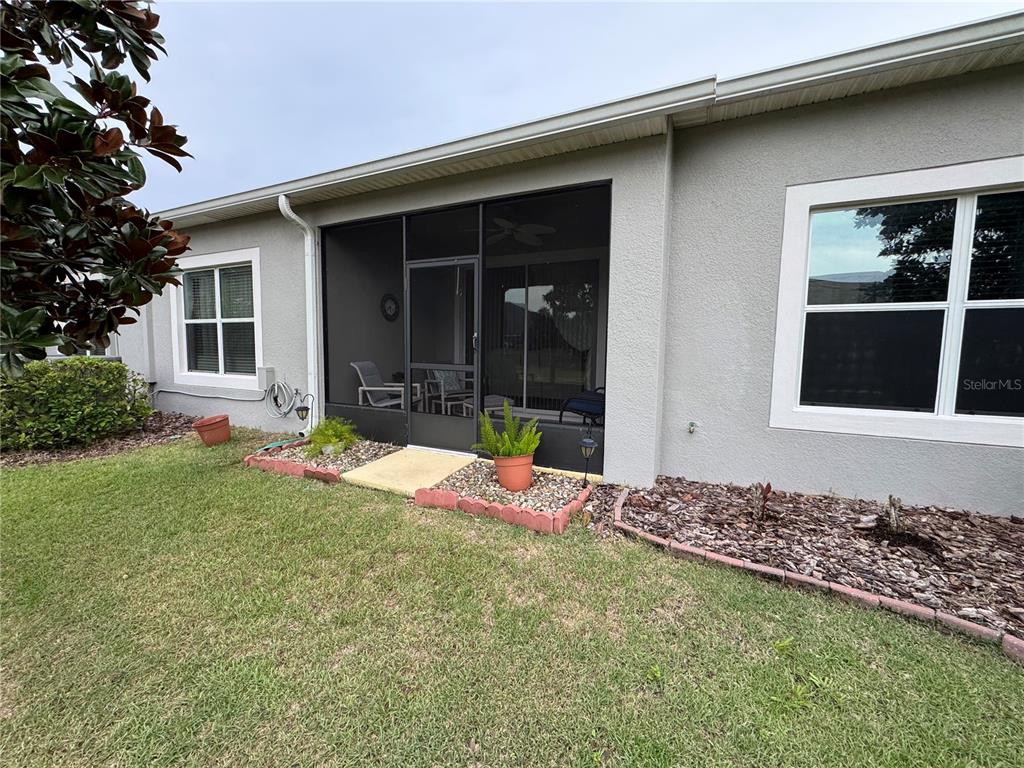 The exterior of a house features a screened-in porch, a lawn, and landscaped garden beds — 3641 SOLANA CIRCLE UNIT B, CLERMONT, FL
