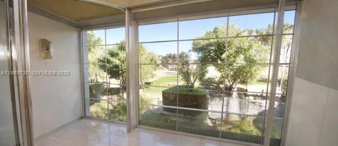 A room with tiled floors and large windows overlooking a grassy yard and trees — 3531 Inverrary Dr # 310, Lauderhill FL 33319, LAUDERHILL, FL