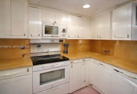 A kitchen features white cabinets, a built-in microwave, a black stove, and light-colored countertops — 3531 Inverrary Dr # 310, Lauderhill FL 33319, LAUDERHILL, FL