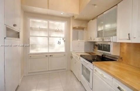 A kitchen features white cabinets, a light wood countertop, a window, and tiled flooring — 3531 Inverrary Dr # 310, Lauderhill FL 33319, LAUDERHILL, FL