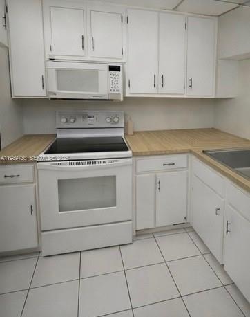 A kitchen features white cabinets, a white electric range, and a built-in microwave — 3531 Inverrary Dr # 310, Lauderhill FL 33319, LAUDERHILL, FL